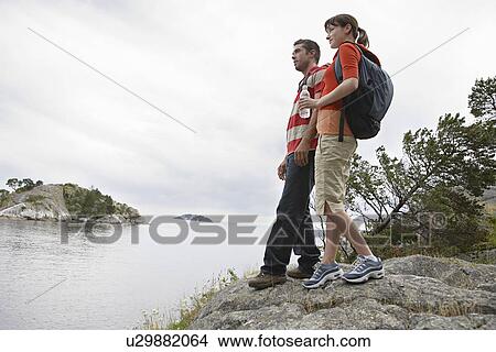Couple standing on rocks beside ocean View Large Photo Image Picture - Couple standing on rocks beside ocean. Fotosearch