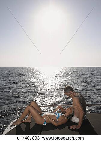 Stock Image - Couple Sunbathing on Boat. Fotosearch