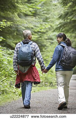 Stock Photo - Couple walking along forest road rear view. Fotosearch