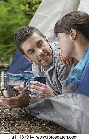 Couple with drinks lying in tent entrance View Large Photo Image Picture - Couple with drinks lying in tent entrance. Fotosearch