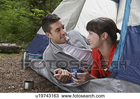 Couple with drinks lying in tent entrance View Large Photo Image Stock Image - Couple with drinks lying in tent entrance. Fotosearch