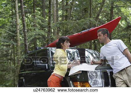 Couple with map on car bonnet in forest View Large Photo Image Stock Image - Couple with map on car bonnet in forest. Fotosearch