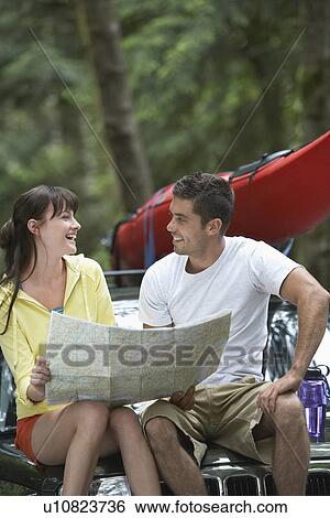 Couple with map sitting on car View Large Photo Image Stock Photograph - Couple with map sitting on car. Fotosearch