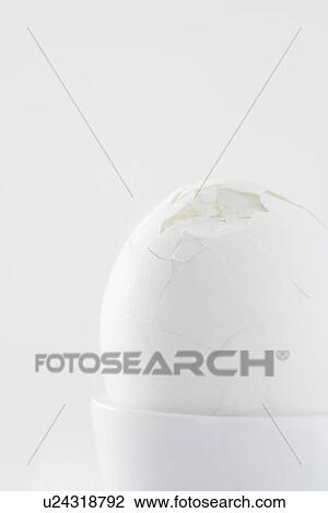 Stock Image - Egg with broken shell in egg cup close up studio shot. Fotosearch