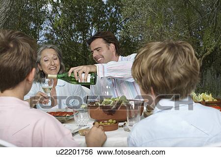 Family with children (6-11) dining in garden man pouring wine View Large Photo Image Stock Photograph - Family with children (6-11) dining in garden man pouring wine. Fotosearch