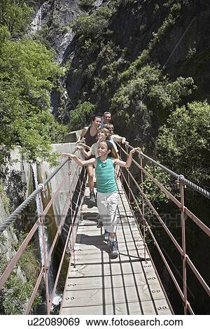 Family with children (7-12) in mountains crossing bridge View Large Photo Image Stock Photo - Family with children (7-12) in mountains crossing bridge. Fotosearch