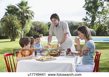 Family with three children (6-11) sitting at breakfast table outdoors View Large Photo Image Stock Image - Family with three children (6-11) sitting at breakfast table outdoors. Fotosearch