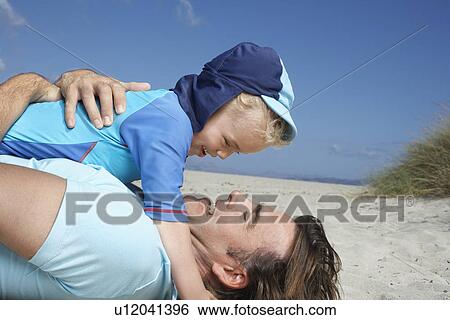 Father playing with young son (3-4) at beach View Large Photo Image Stock Photograph - Father playing with young son (3-4) at beach. Fotosearch