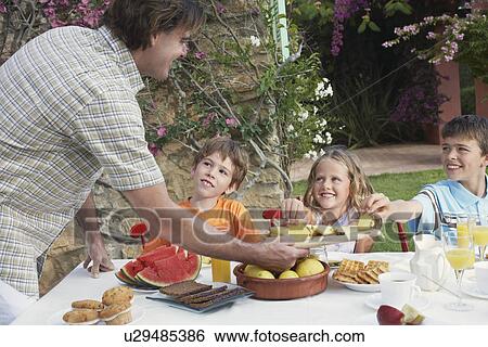 Father serving slices of pineapple to children (6-11) sitting at outdoor table View Large Photo Image Stock Photograph - Father serving slices of pineapple to children (6-11) sitting at outdoor table. Fotosearch