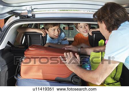 Stock Image - Father talking to boys (6-11) sitting in loaded car. Fotosearch