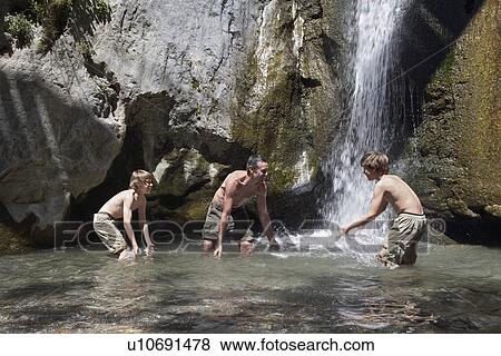 Father with two sons (7-12) splashing in river View Large Photo Image Stock Photo - Father with two sons (7-12) splashing in river. Fotosearch