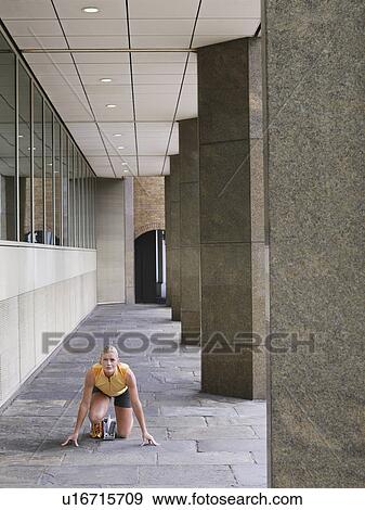 Female athelete crouching on pavement by pillars View Large Photo Image Stock Photo - Female athelete crouching on pavement by pillars. Fotosearch