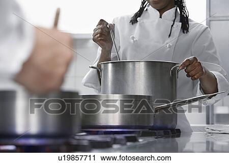 Stock Image - Female chef cooking in kitchen. Fotosearch