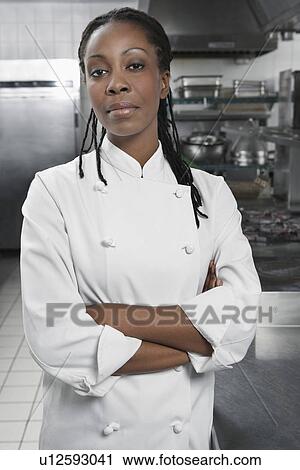 Stock Image - Female chef with arms crossed in kitchen portrait. Fotosearch