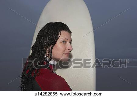 Female surfer holding surfboard in shallow water at dusk View Large Photo Image Stock Photography - Female surfer holding surfboard in shallow water at dusk. Fotosearch