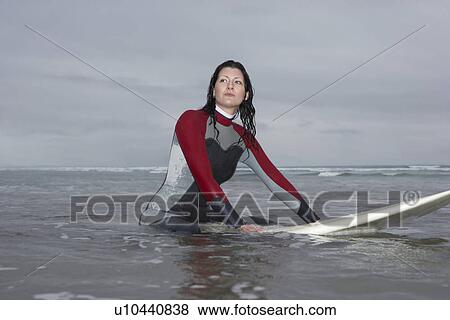 Female surfer sitting on surfboard in water low angle view View Large Photo Image Stock Photo - Female surfer sitting on surfboard in water low angle view. Fotosearch