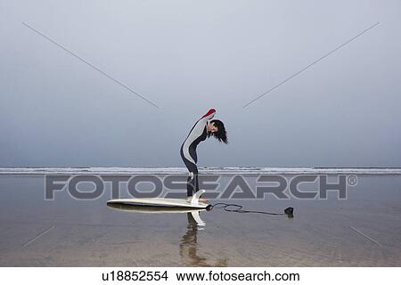Picture - Female surfer standing in shallow water side view. Fotosearch