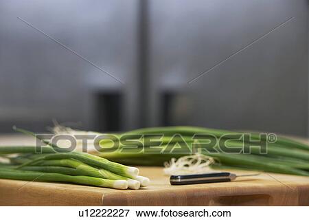 Fresh spring onions and knife on chopping board close-up View Large Photo Image Stock Photo - Fresh spring onions and knife on chopping board close-up. Fotosearch