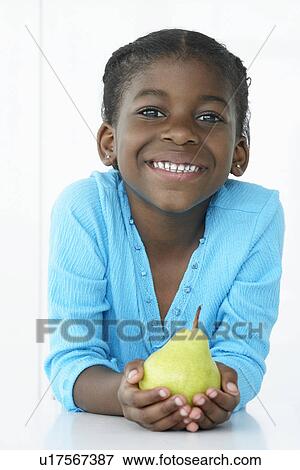 Girl (5-6) holding pear and smiling portrait View Large Photo Image Stock Photo - Girl (5-6) holding pear and smiling portrait. Fotosearch