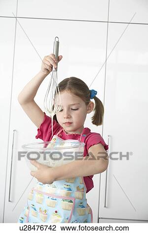 Stock Image - Girl (5-6) preparing food in bowl using wire whisk. Fotosearch