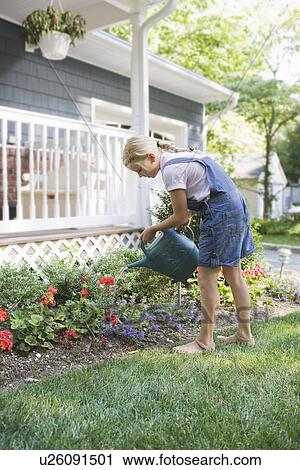 Girl (7-9) watering flowers at house back yard View Large Photo Image Stock Image - Girl (7-9) watering flowers at house back yard. Fotosearch