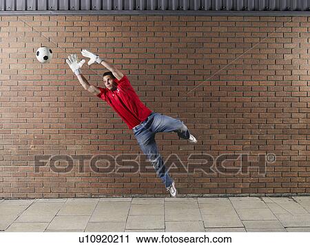 Goalkeeper reaching for football against brick wall View Large Photo Image Stock Image - Goalkeeper reaching for football against brick wall. Fotosearch