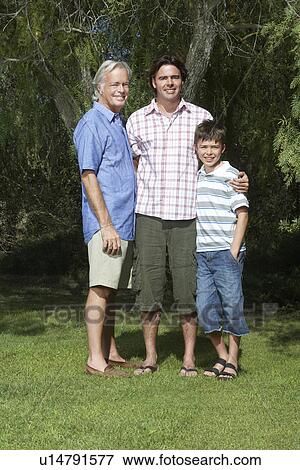 Stock Photo - Grandfather father and son (10-12) posing under tree. Fotosearch