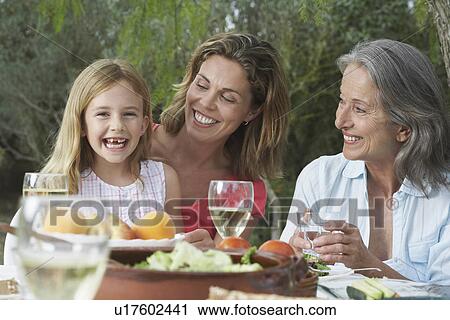 Grandma mother and daughter (5-6) sitting at table in garden girl laughing View Large Photo Image Stock Image - Grandma mother and daughter (5-6) sitting at table in garden girl laughing. Fotosearch