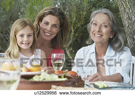Grandma mother and daughter (5-6) sitting at table in garden View Large Photo Image Stock Photograph - Grandma mother and daughter (5-6) sitting at table in garden. Fotosearch