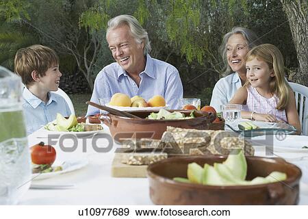 Grandparents with grandchildren (5-6) sitting at garden table View Large Photo Image Stock Photo - Grandparents with grandchildren (5-6) sitting at garden table. Fotosearch