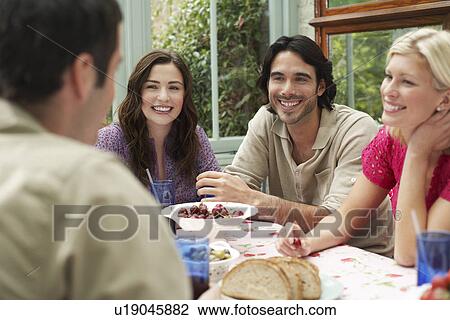 Group of young people sitting at verandah table laughing View Large Photo Image Stock Image - Group of young people sitting at verandah table laughing. Fotosearch