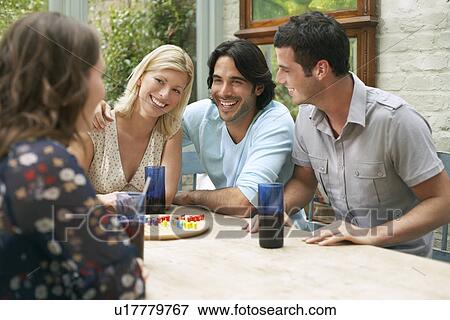 Group of young people sitting at verandah table laughing View Large Photo Image Stock Photo - Group of young people sitting at verandah table laughing. Fotosearch