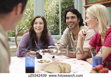 Group of young people sitting at verandah table laughing View Large Photo Image Stock Photo - Group of young people sitting at verandah table laughing. Fotosearch