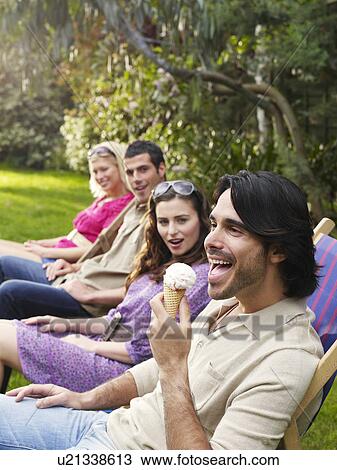 Group of young people sitting in row on deckchairs in garden side view View Large Photo Image Stock Image - Group of young people sitting in row on deckchairs in garden side view. Fotosearch