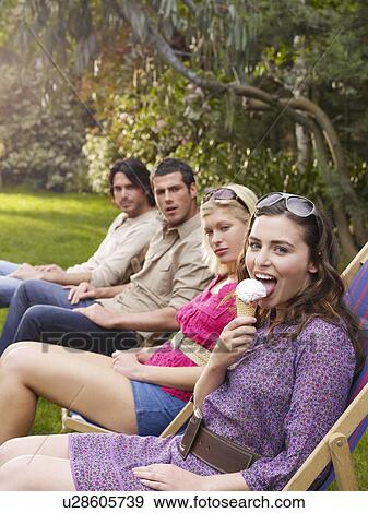 Group of young people sitting in row on deckchairs in garden side view View Large Photo Image Stock Photo - Group of young people sitting in row on deckchairs in garden side view. Fotosearch