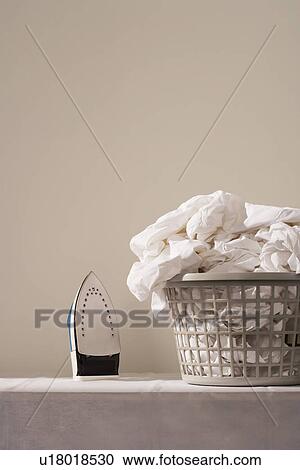 Iron next to laundry basket on table View Large Photo Image Stock Image - Iron next to laundry basket on table. Fotosearch