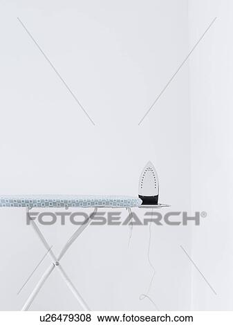 Iron on ironing board against white wall View Large Photo Image Stock Photo - Iron on ironing board against white wall. Fotosearch