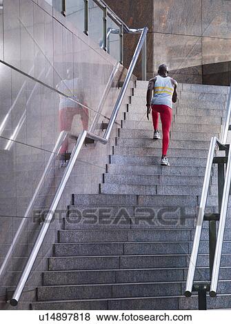 Stock Photo - Male athlete running up staircase outside building. Fotosearch