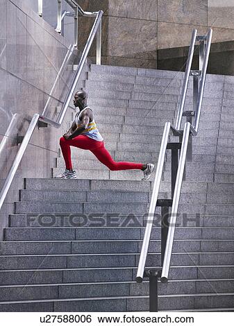 Male athlete stretching on staircase outside building View Large Photo Image Stock Photograph - Male athlete stretching on staircase outside building. Fotosearch