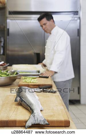 Male chef in kitchen focus on salmon in foreground View Large Photo Image Stock Photo - Male chef in kitchen focus on salmon in foreground. Fotosearch