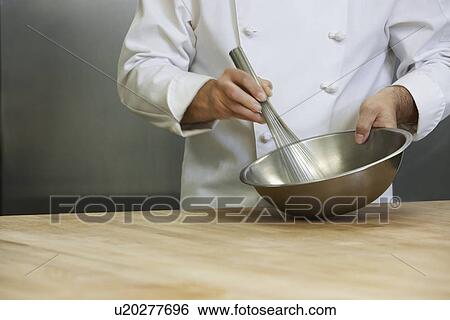 Stock Photograph - Male chef mixing ingredients using whisk mid section. Fotosearch