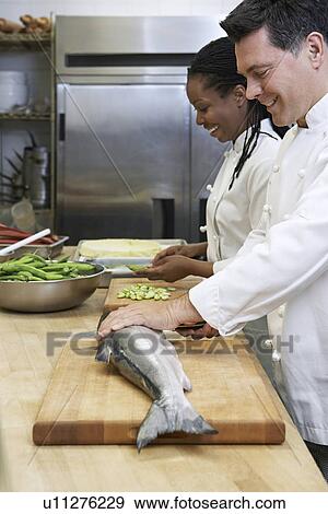 Male chef preparing salmon beside colleague in kitchen View Large Photo Image Stock Photo - Male chef preparing salmon beside colleague in kitchen. Fotosearch