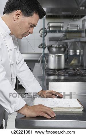 Male chef reading recipe book in kitchen View Large Photo Image Stock Image - Male chef reading recipe book in kitchen. Fotosearch