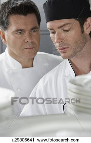 Male chef supervising trainee in kitchen View Large Photo Image Stock Image - Male chef supervising trainee in kitchen. Fotosearch