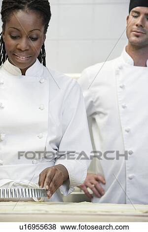 Male chef watching female chef preparing food in kitchen View Large Photo Image Stock Photo - Male chef watching female chef preparing food in kitchen. Fotosearch