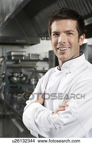 Picture - Male chef with arms crossed in kitchen portrait. Fotosearch