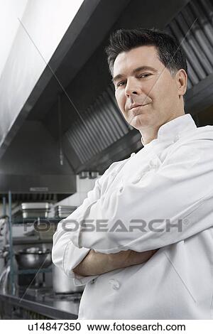 Stock Image - Male chef with arms crossed in kitchen portrait. Fotosearch