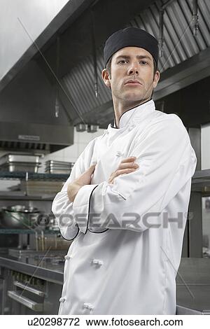 Stock Image - Male chef with arms crossed in kitchen portrait. Fotosearch