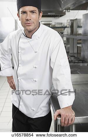 Picture - Male chef with hand on hip in kitchen portrait. Fotosearch