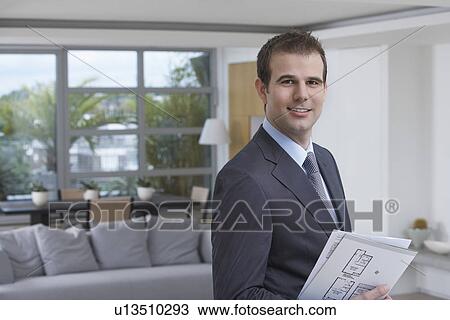 Male estate agent holding brochure in new home portrait View Large Photo Image Stock Image - Male estate agent holding brochure in new home portrait. Fotosearch